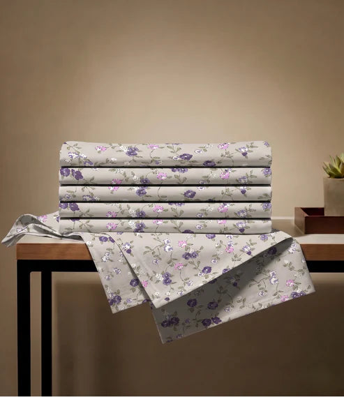 Folded queen size 100% pure cotton floral bedsheet showcasing a premium beige fabric with purple botanical prints, highlighting breathable cotton quality and elegant craftsmanship.