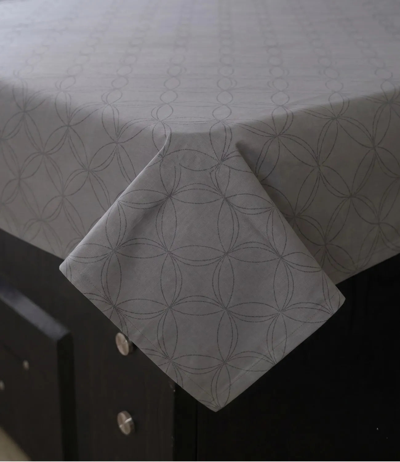 Close-up of a premium 100% pure cotton dark grey geometric bedsheet showcasing its smooth drape, breathable weave, fine stitching, and elegant circular pattern.