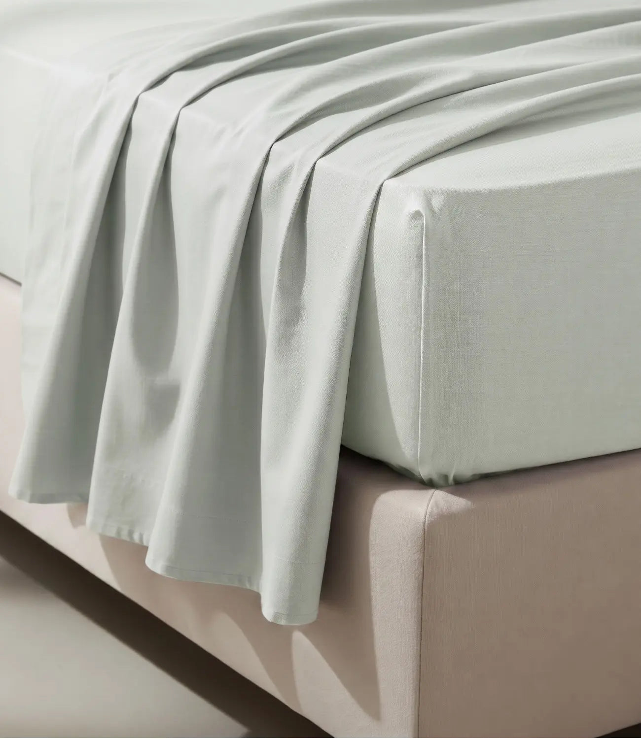 Close-up of a mint green king size fitted cotton bedsheet draped over a mattress, showcasing its smooth weave, neat corners, and breathable fabric for a comfortable and secure fit.
