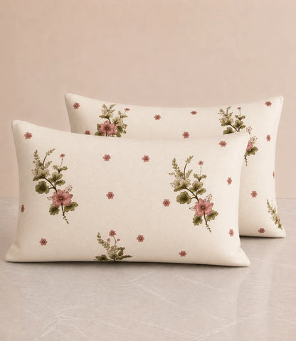 Two matching cotton pillow covers with pink floral bouquet prints, green leafy details, and small scattered blossoms on an ivory base, highlighting the coordinated bedding design.