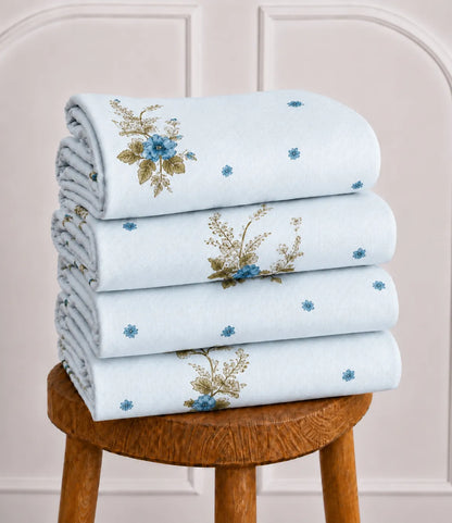 Neatly folded light blue cotton bedsheet displaying blue floral bouquet patterns and fine dotted detailing, highlighting the fabric's smooth finish and elegant design.