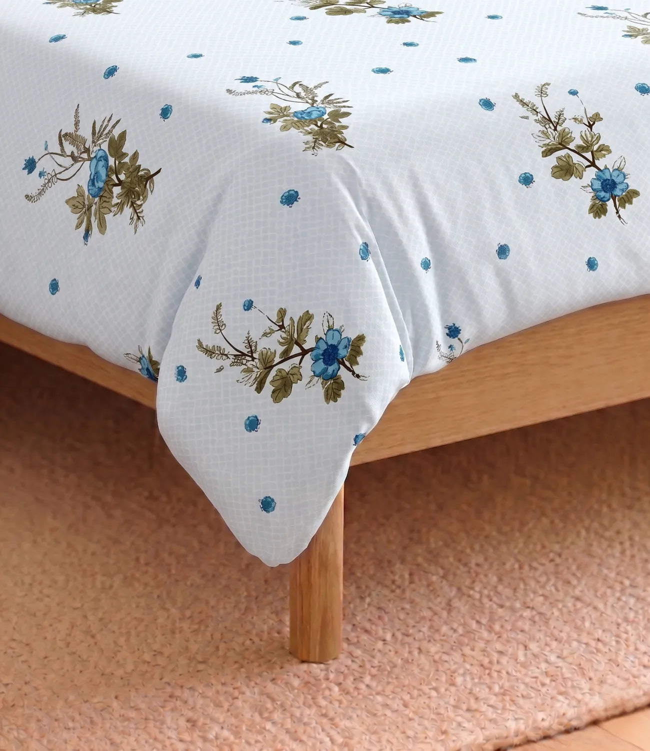 Close-up of the light blue cotton bedsheet featuring intricate blue floral bouquets, scattered dotted motifs, and a soft woven texture, showcasing the fabric quality and print details.
