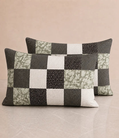 Set of two matching cotton pillow covers featuring a contemporary patchwork pattern with black, grey, sage green, and white square blocks on a neutral background.