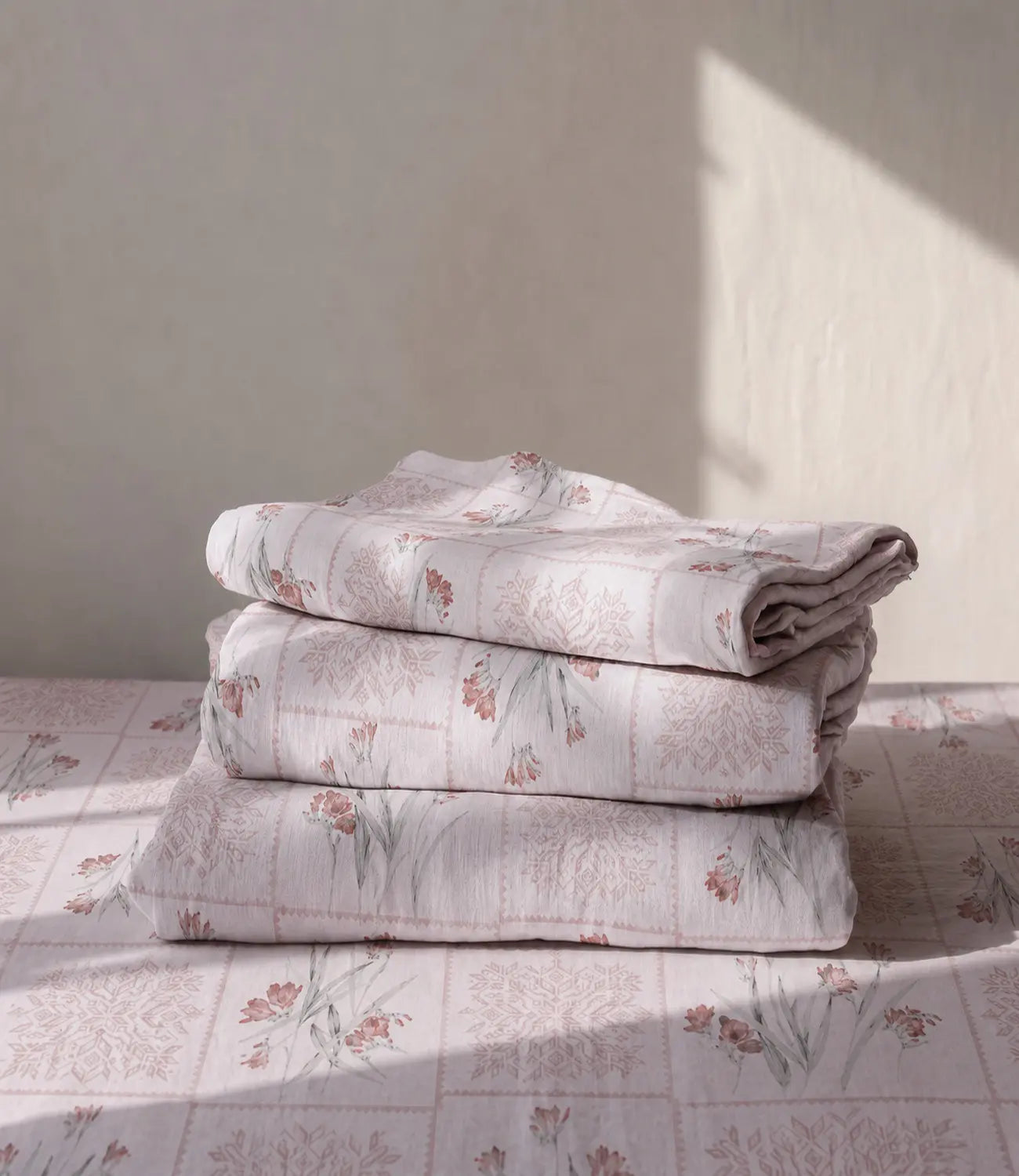 Folded premium blush pink cotton bedsheet showcasing soft floral botanical prints, geometric patterns, and breathable 100% cotton fabric.