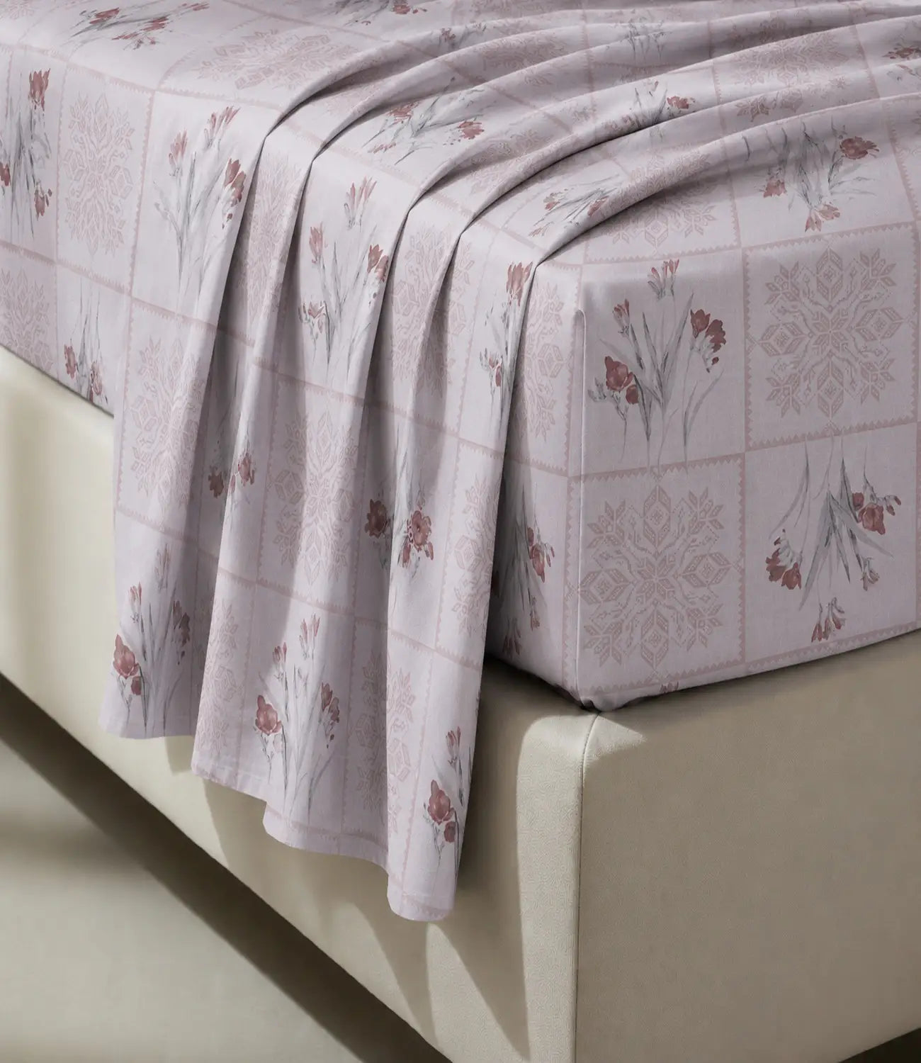 Close-up of a blush pink 100% cotton bedsheet highlighting delicate floral prints, geometric block pattern, soft fabric texture, and elegant drape.
