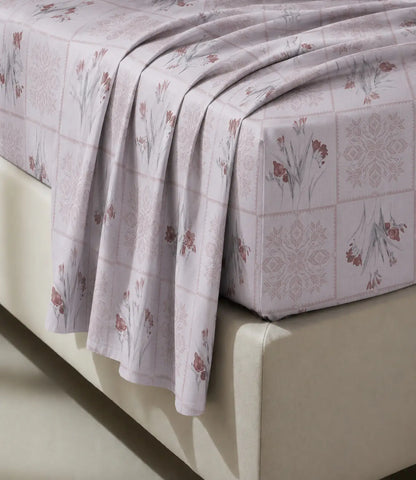 Close-up of a blush pink 100% cotton bedsheet highlighting delicate floral prints, geometric block pattern, soft fabric texture, and elegant drape.