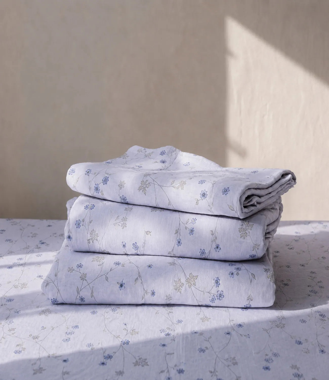 Folded premium ivory cotton bedsheet with delicate blue floral vine pattern crafted from breathable 100% cotton fabric for everyday comfort.