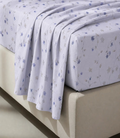Close-up of an ivory 100% cotton bedsheet highlighting delicate blue floral vine print, soft cotton texture, elegant drape, and premium fabric finish.