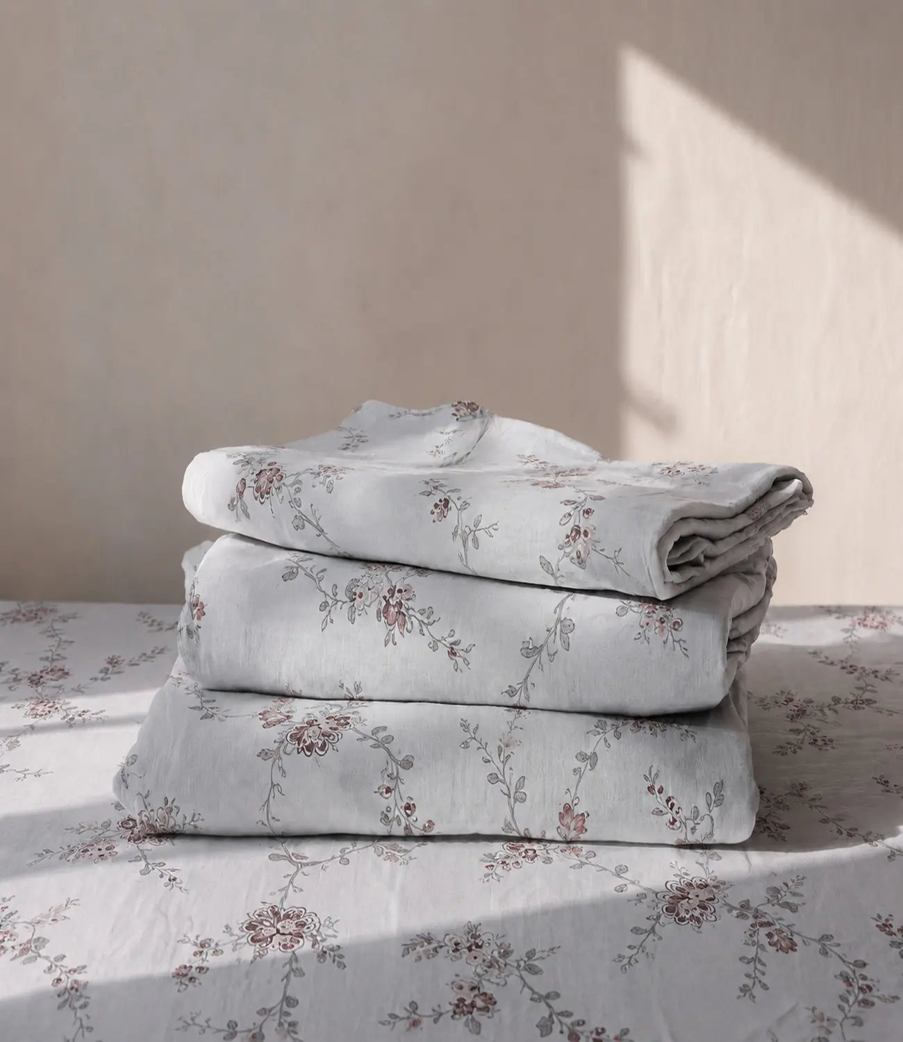 Folded premium ivory cotton bedsheet with delicate dusty rose floral vine pattern crafted from breathable 100% cotton fabric for everyday comfort.