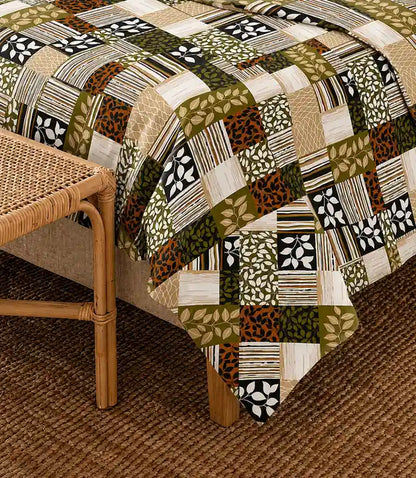Close-up of a premium 100% cotton earthy patchwork bedsheet featuring olive green, beige, cream, black, and rust geometric and botanical blocks with soft breathable fabric.