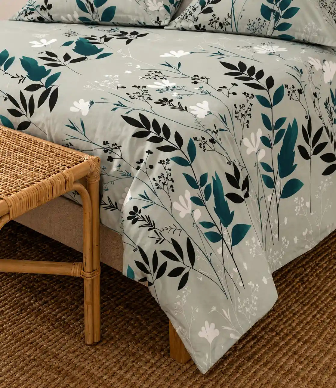 Close-up of a premium cotton bedsheet featuring an elegant sage green botanical leaf and floral print with a soft, smooth fabric finish.