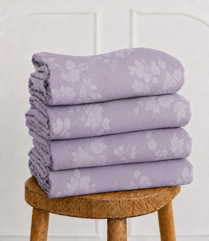 Folded lavender floral king size bed sheet set showcasing a delicate white floral pattern and smooth, breathable cotton fabric.