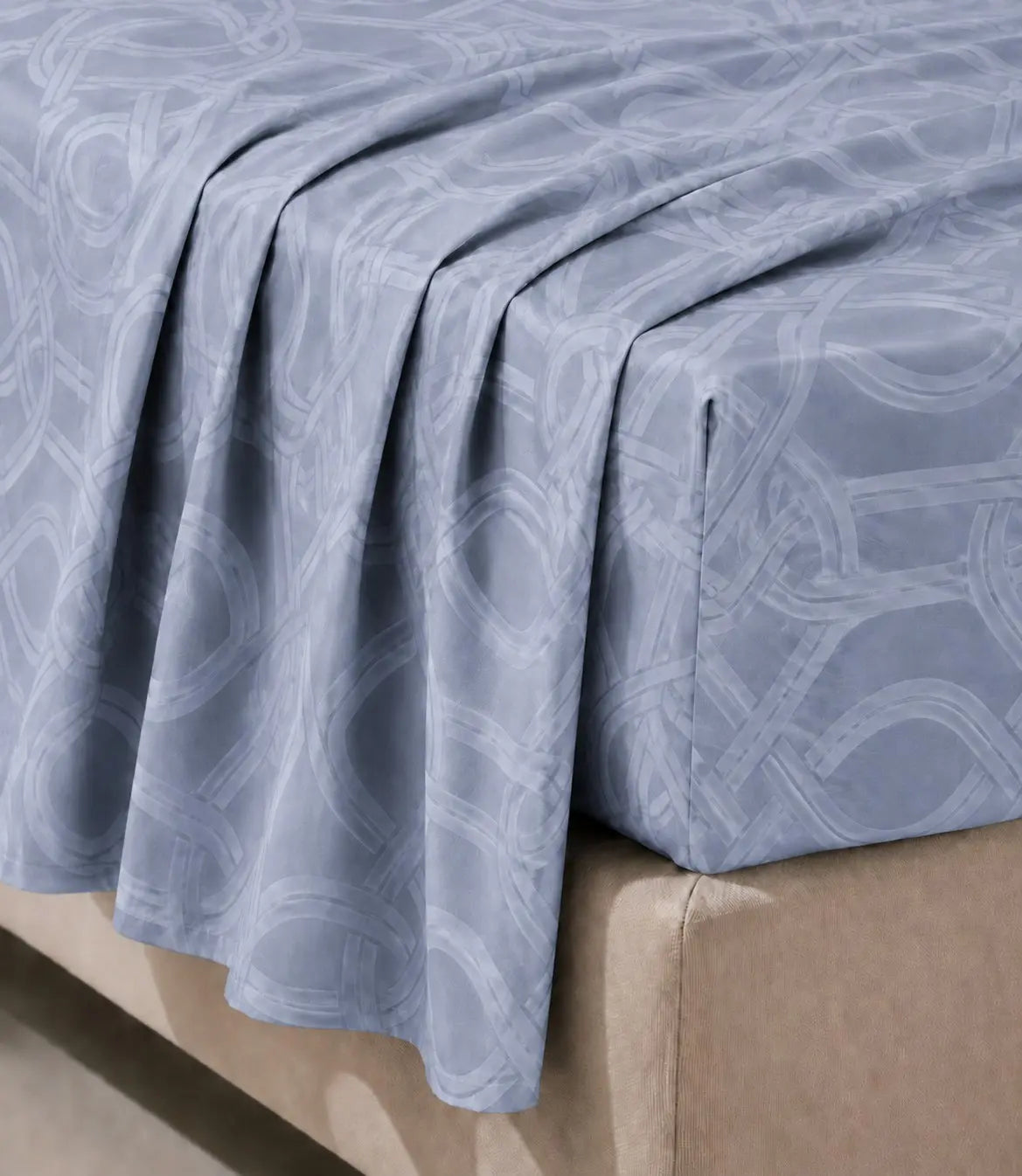 Close-up of powder blue cotton bedsheet highlighting soft fabric texture, smooth drape, and modern geometric pattern.