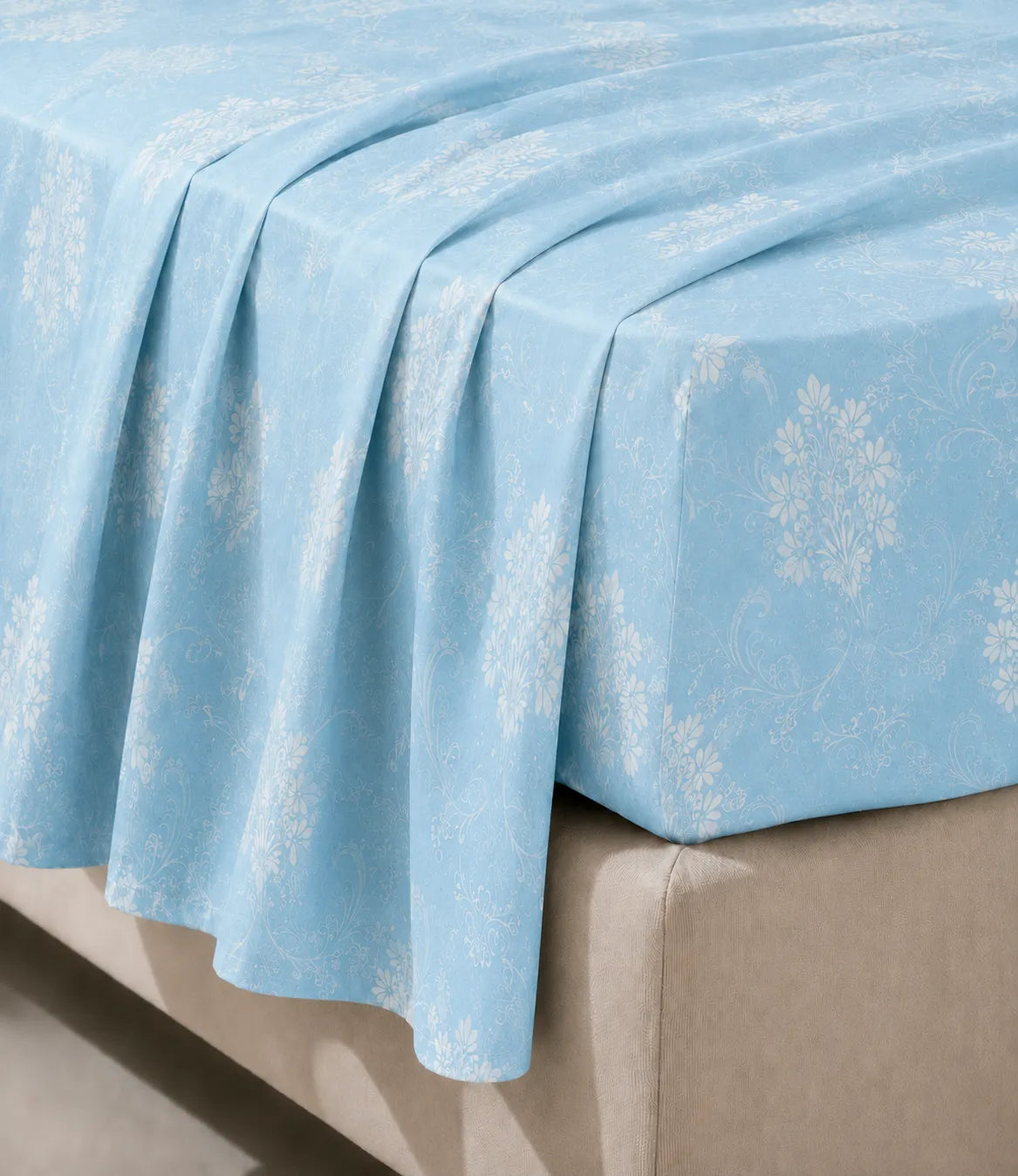 Close-up of a king size sky blue cotton bedsheet highlighting the soft fabric texture, smooth drape, and intricate white floral vine pattern.