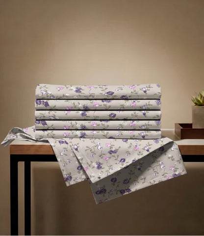 Folded queen size 100% pure cotton floral bedsheet showcasing a premium beige fabric with purple botanical prints, highlighting breathable cotton quality and elegant craftsmanship.