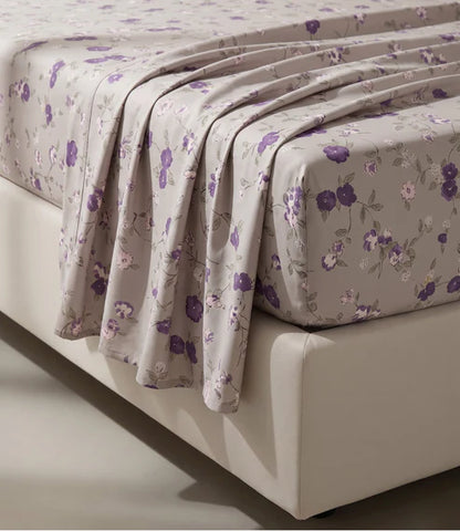 Close-up of a premium 100% pure cotton floral bedsheet displaying its soft breathable fabric, smooth cotton weave, and elegant purple botanical pattern with a luxurious drape.