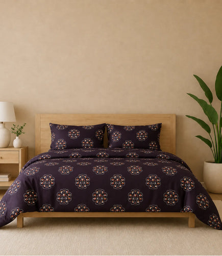 Queen size cotton bedsheet in midnight plum with elegant floral motifs, styled on a wooden bed in a modern bedroom with two matching pillow covers.