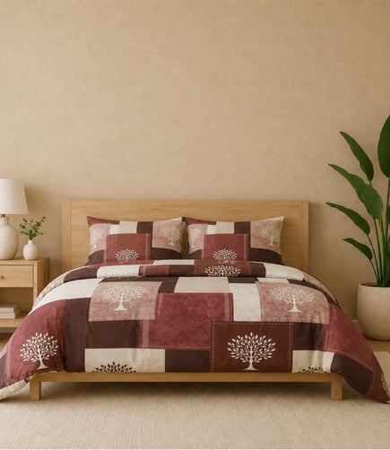 Queen-size cotton bedsheet set featuring a rustic patchwork design in maroon, brown, beige, and cream with elegant white tree motifs. Displayed on a wooden bed with two matching pillow covers in a warm, modern bedroom setting.