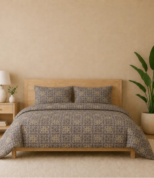 Premium queen size 100% pure cotton bedsheet featuring an elegant taupe geometric mosaic print with intricate heritage-inspired motifs in taupe, brown, beige, and subtle rust accents, styled in a modern wooden bedroom with matching pillow covers for a warm and sophisticated ambience.
