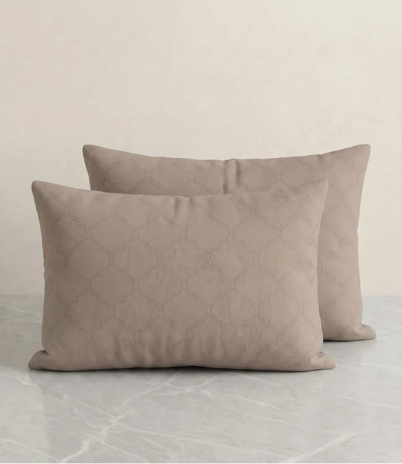 Set of two beige geometric printed pillow covers displayed on a marble surface, highlighting the elegant all-over pattern and soft fabric.