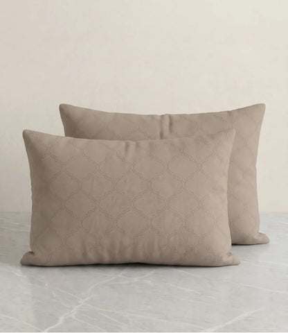 Set of two beige geometric printed pillow covers displayed on a marble surface, highlighting the elegant all-over pattern and soft fabric.