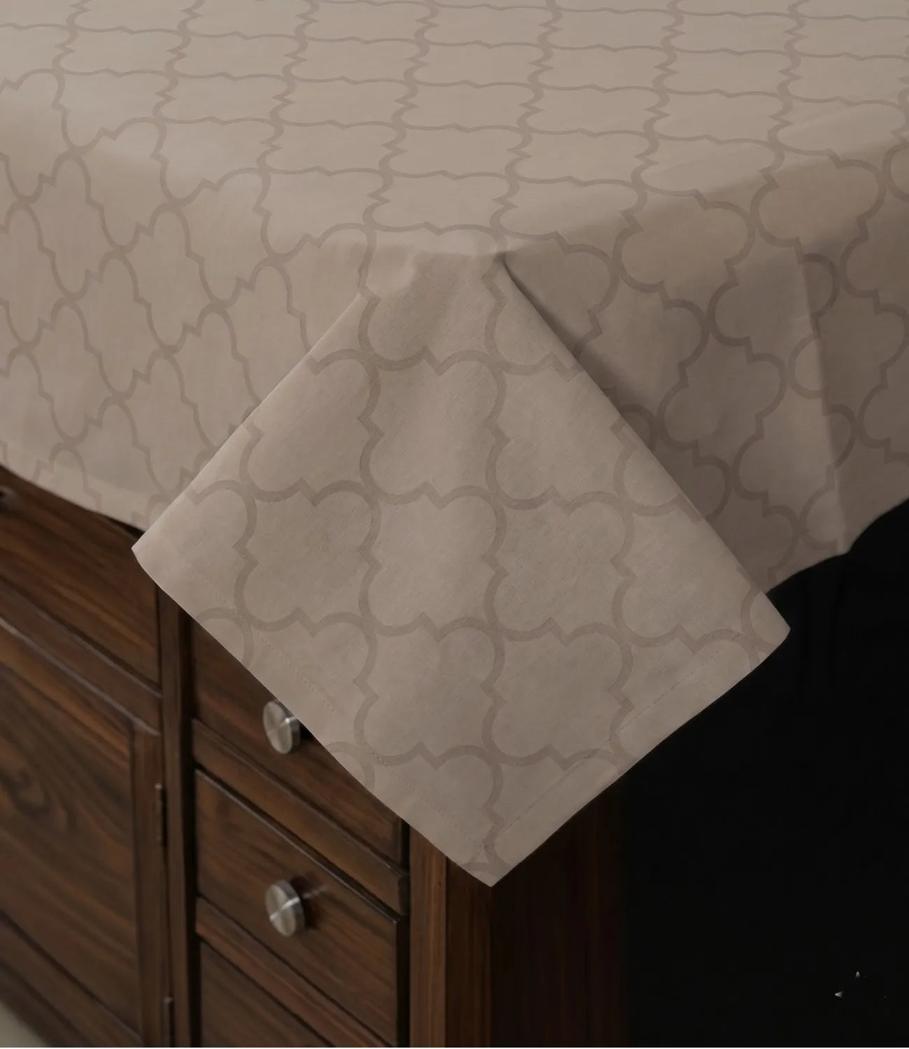 Close-up of the beige geometric bedsheet corner draped over the bed, showcasing the fine weave, stitching, and subtle contemporary pattern.