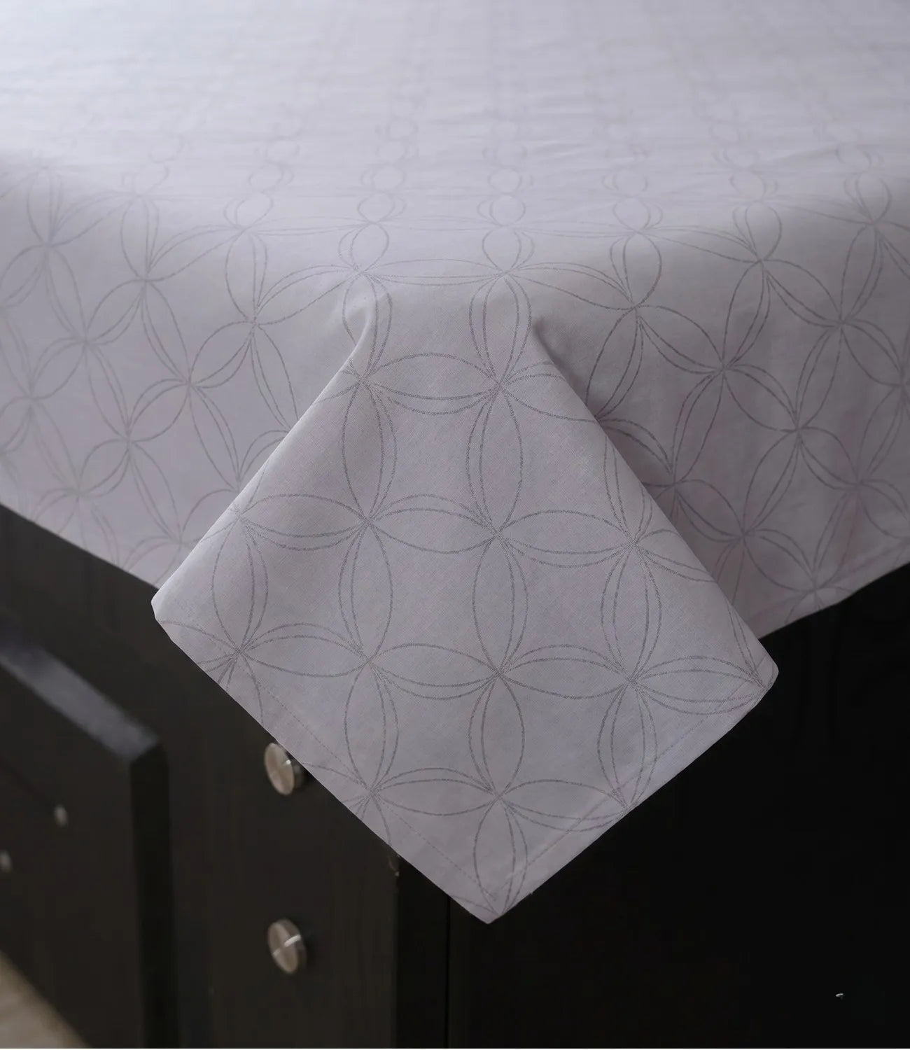 Close-up of a premium 100% pure cotton silver grey geometric bedsheet showcasing its smooth drape, breathable weave, fine stitching, and elegant circular pattern.