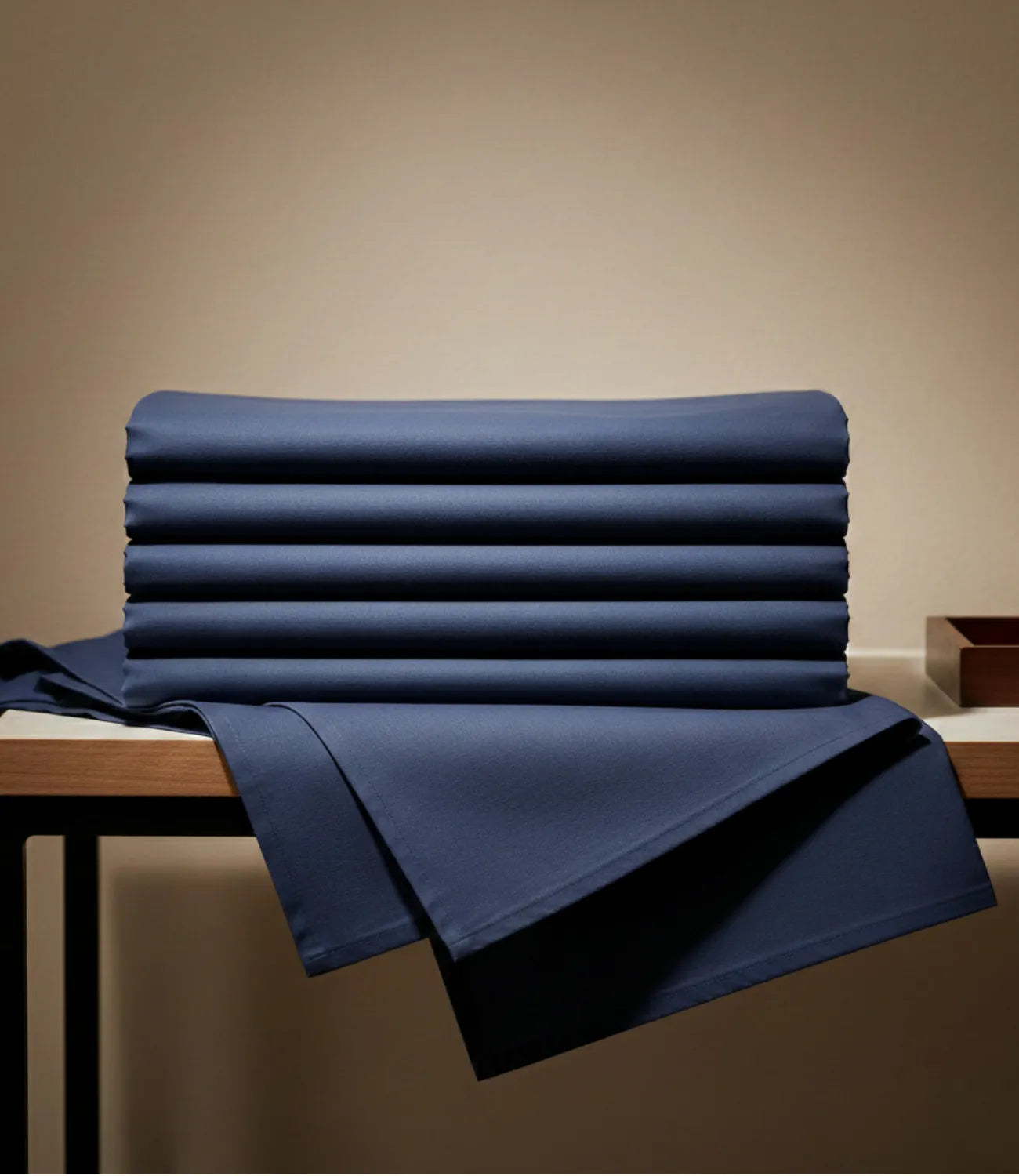 Neatly folded Soft Heaven navy blue king size cotton bedsheet set displayed on a wooden table, emphasizing premium stitching, durable fabric, and elegant presentation.