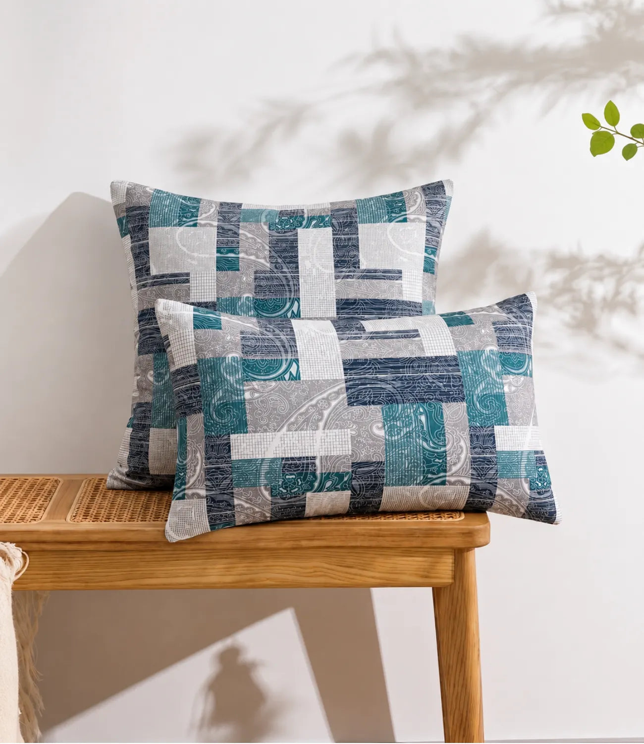 Teal geometric patchwork cotton pillow covers featuring modern abstract block patterns displayed on a wooden console table.